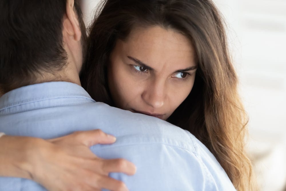 Couple hugging unhappily.