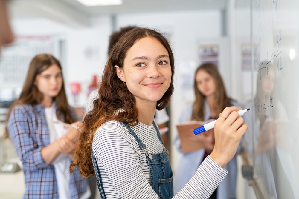 Schoolgirl at the board solving a problem.
