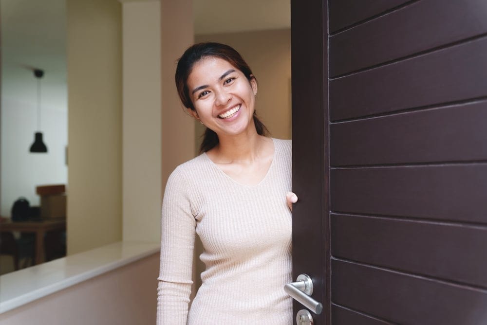 Smiling Woman opening her front door.