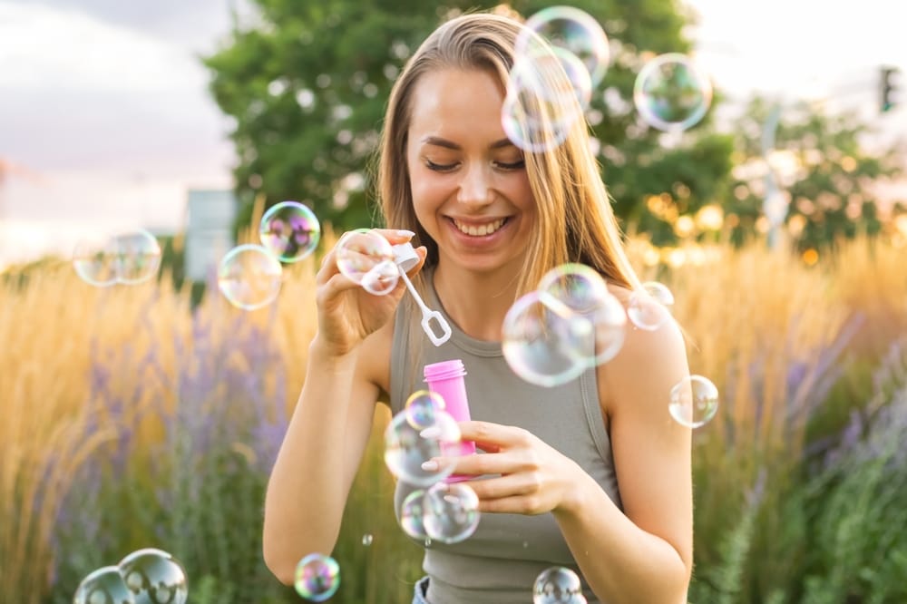 Happy,Young,Woman,With,Long,Loose,Hair,Blows,Soap,Bubbles