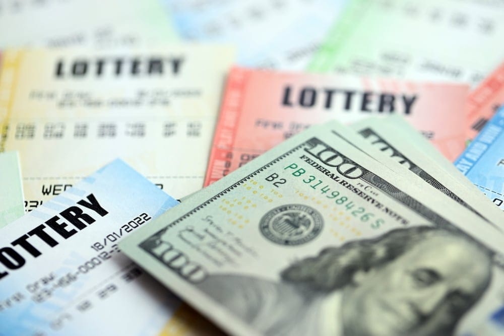 Stack of money on top of lottery tickets.