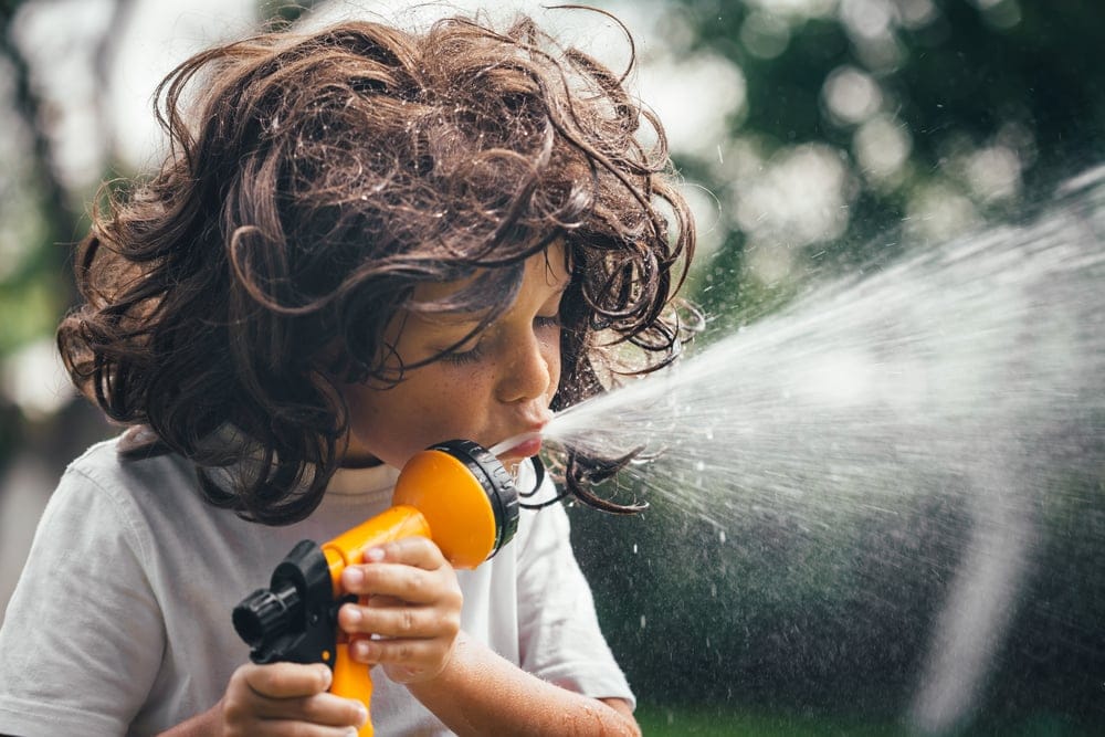 Child plays with a hose outside.