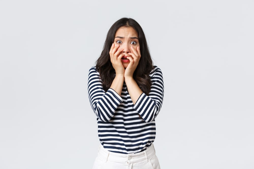 Woman with her face in her hands looking insecure.