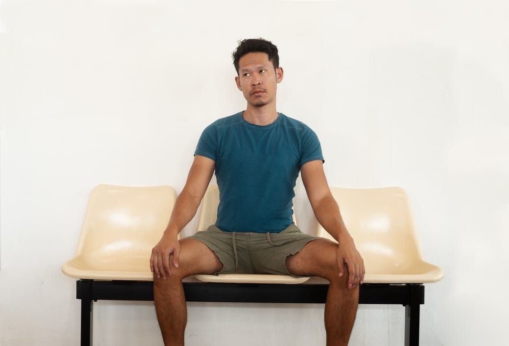 An,Asian,Man,Sitting,On,A,Bench,Looking,Bored