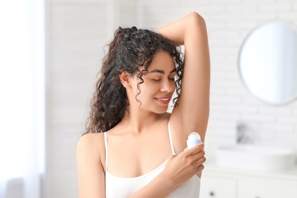Woman applying deodarant.
