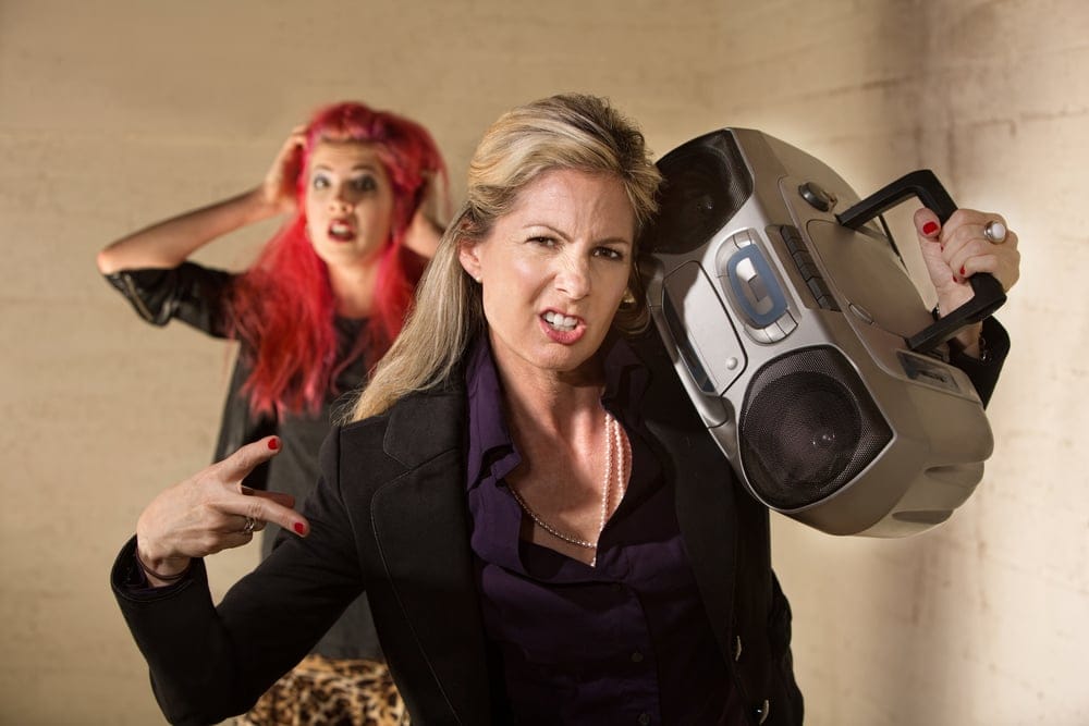 Two women holding a boom box radio.