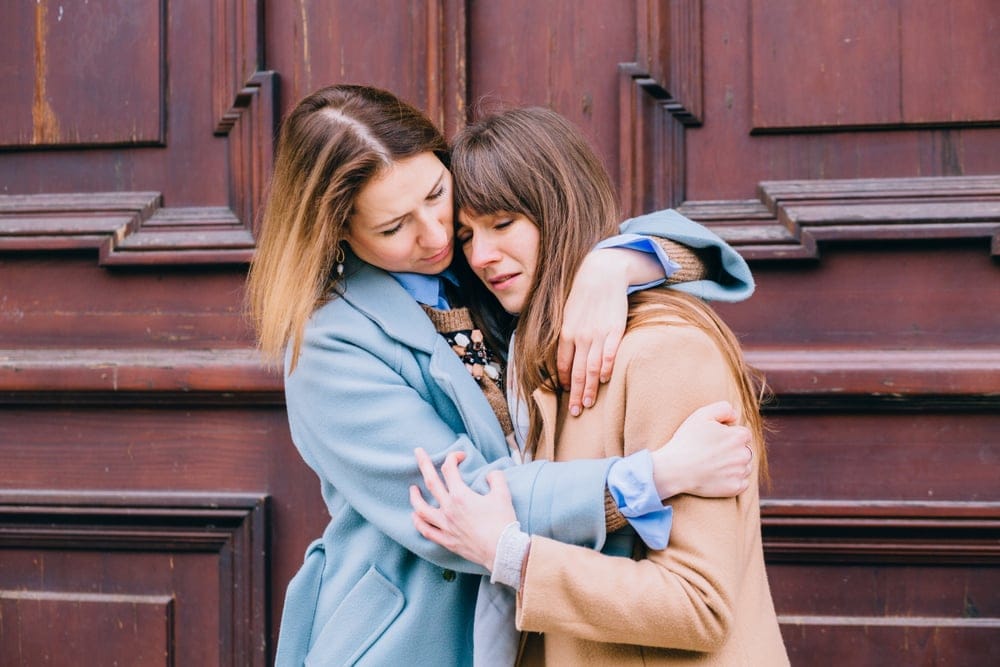 Two women embracing on doorstep.