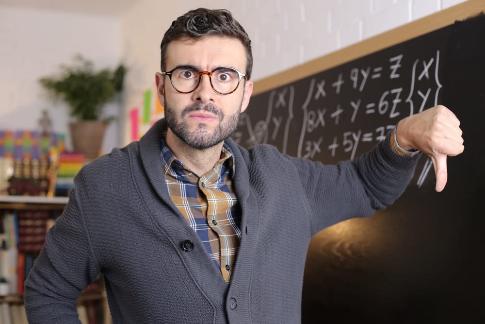 Teacher in front of a blackboard full of numbers.