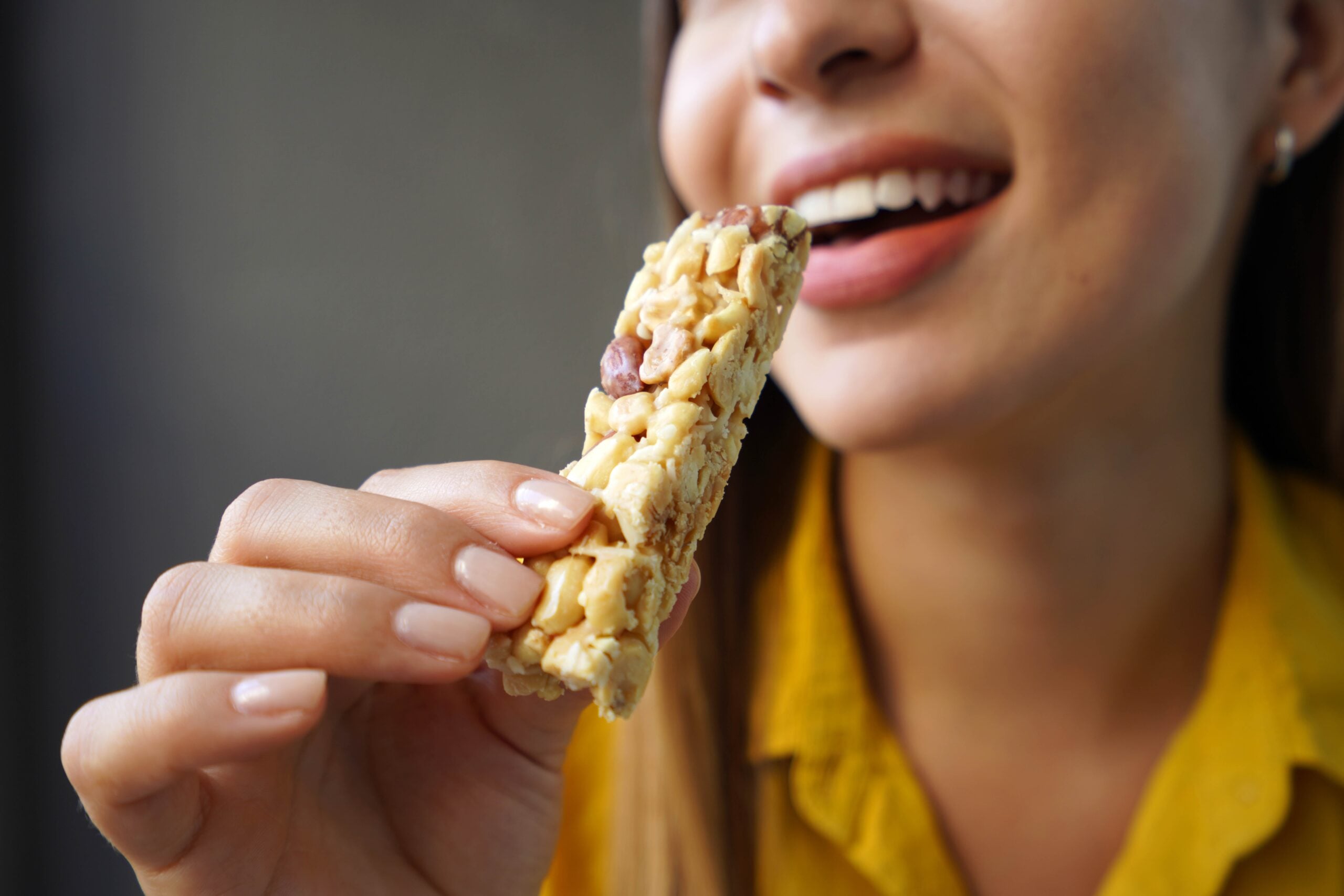 Woman eating a granola bar.