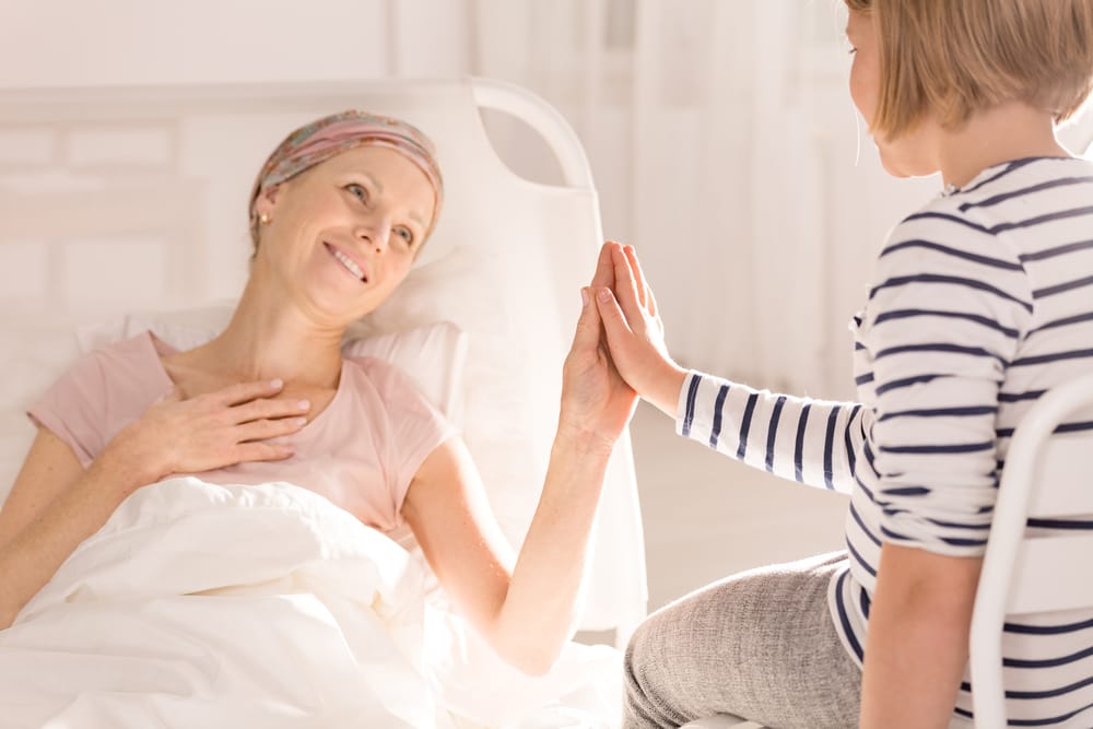 Woman laying in a hospital bed with a child visitor.