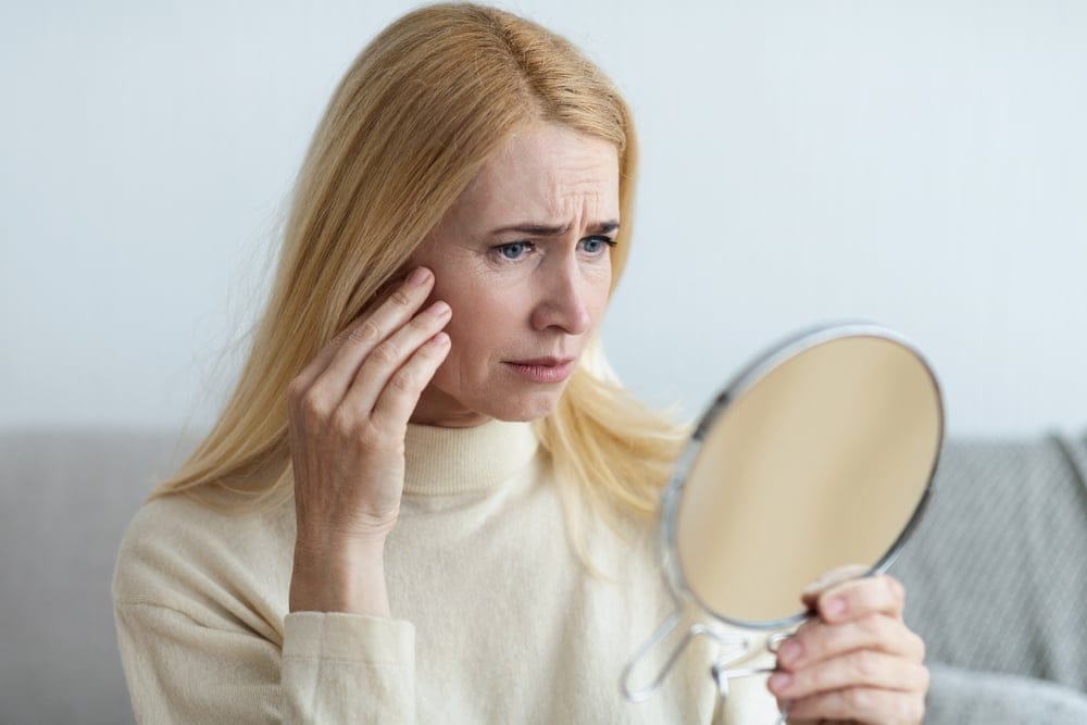 Woman looking at her skin on the mirror.
