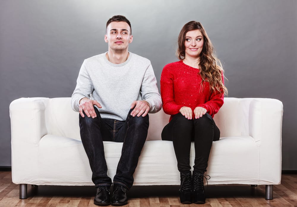 Man and woman sitting near one another not speaking.