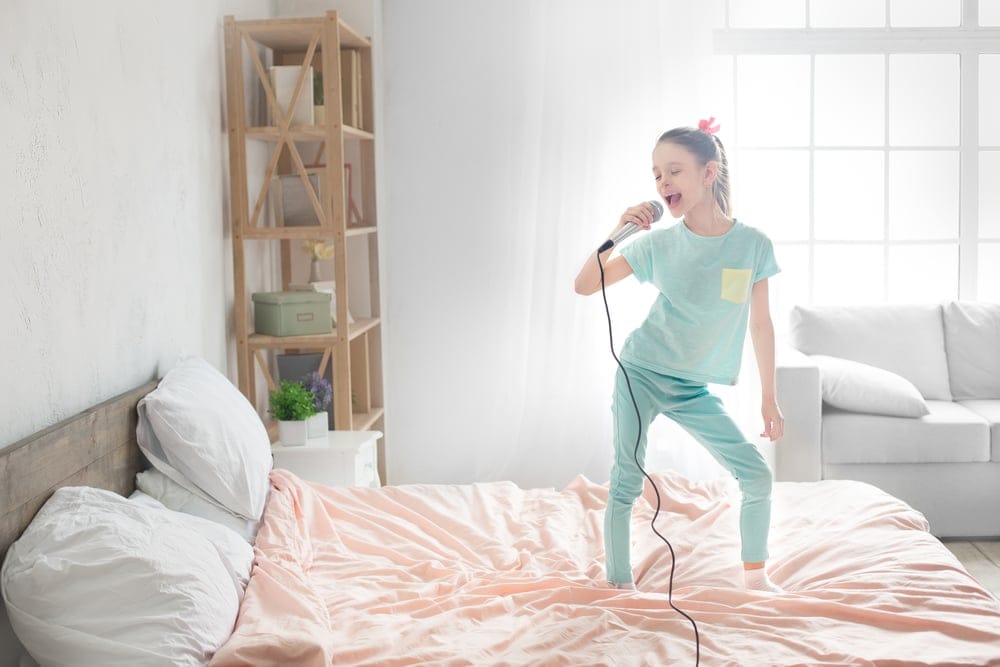 Teenage girl alone singing in bed.
