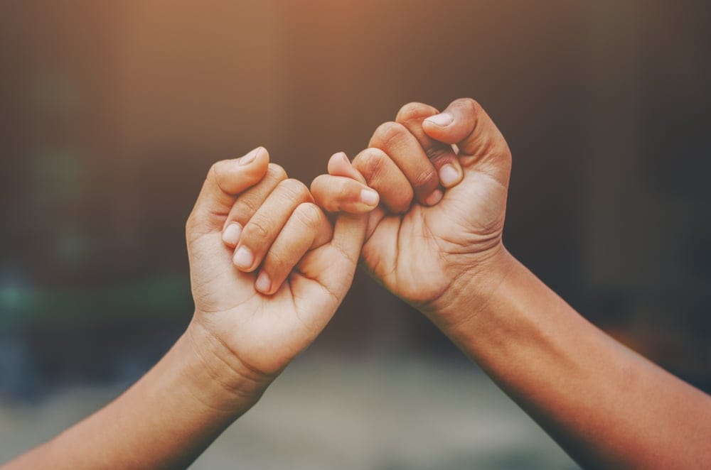 Linked pinkies of two hands.