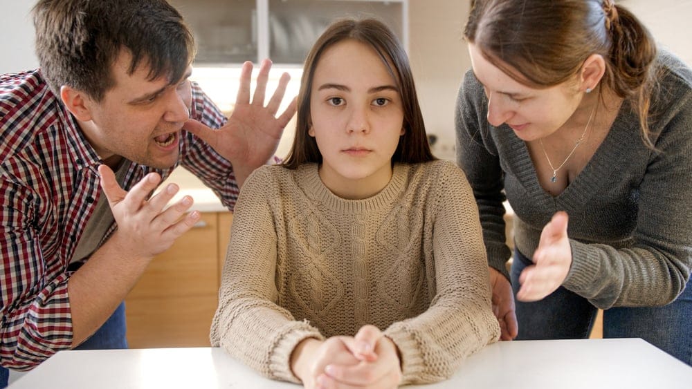 Parents,Yelling,And,Shouting,At,Teenage,Daughter,Sittin,Behind,Table