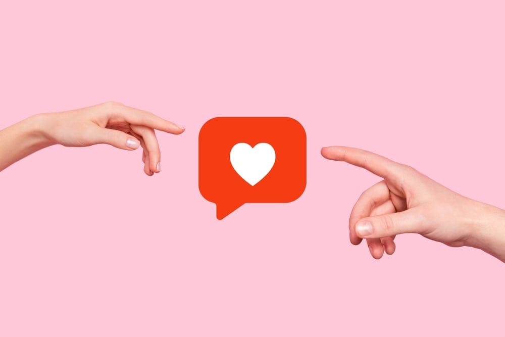 Two hands pointing to a heart emoji.