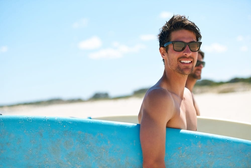 Man holding a surf board on the beach.