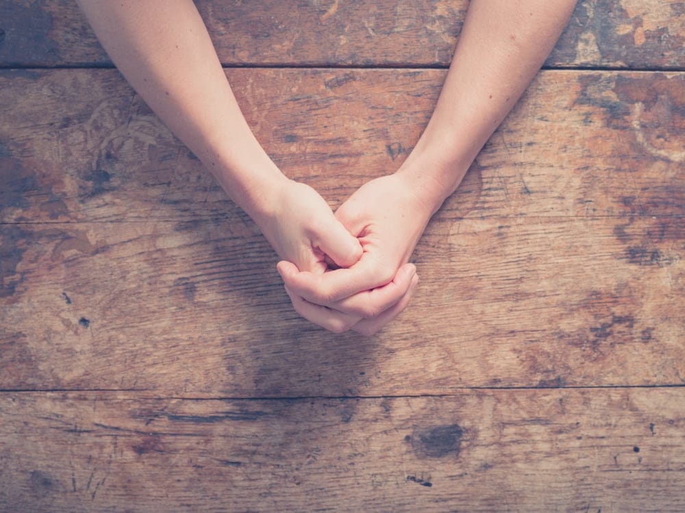 Female hands clasped together.