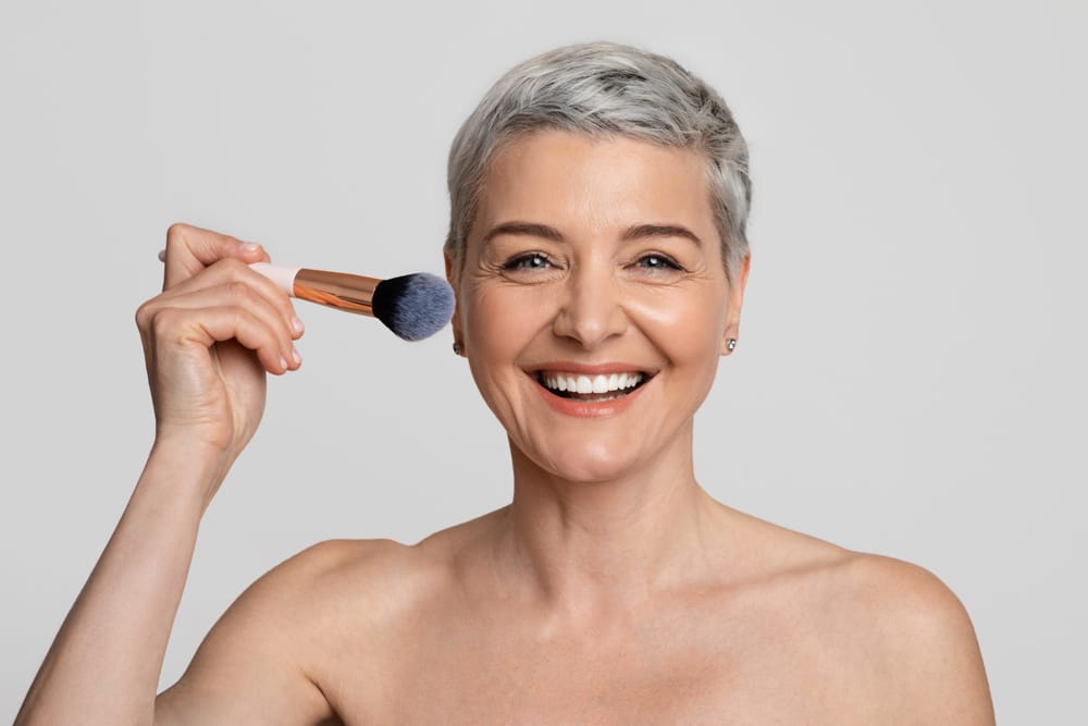 Mature woman putting makeup on.