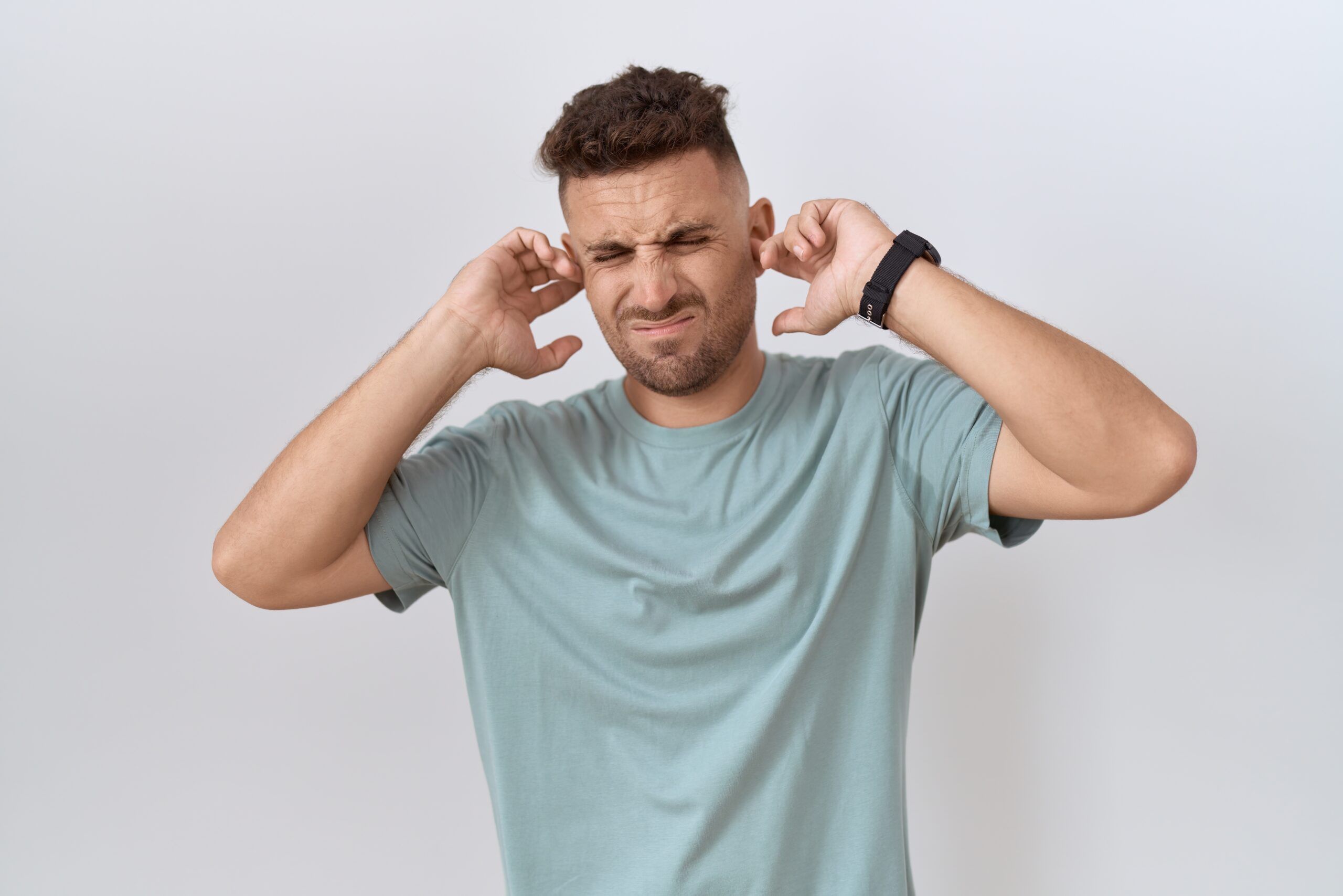 A young man plugging his ears.