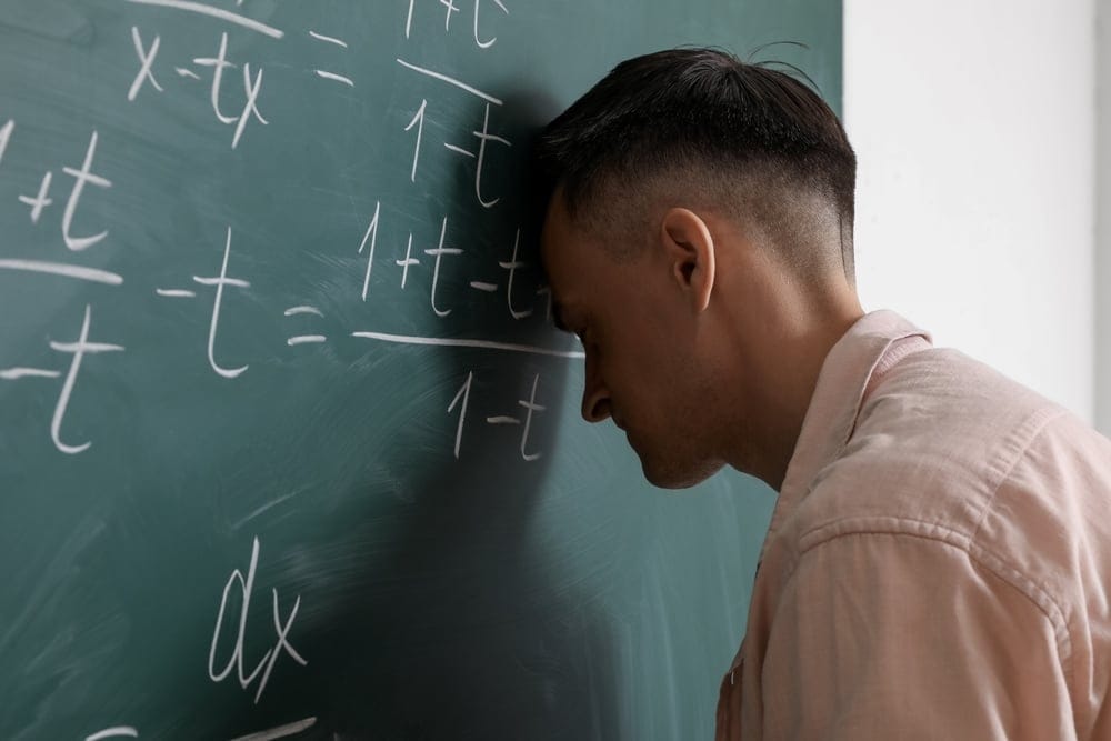 Exhausted math teacher at blackboard.
