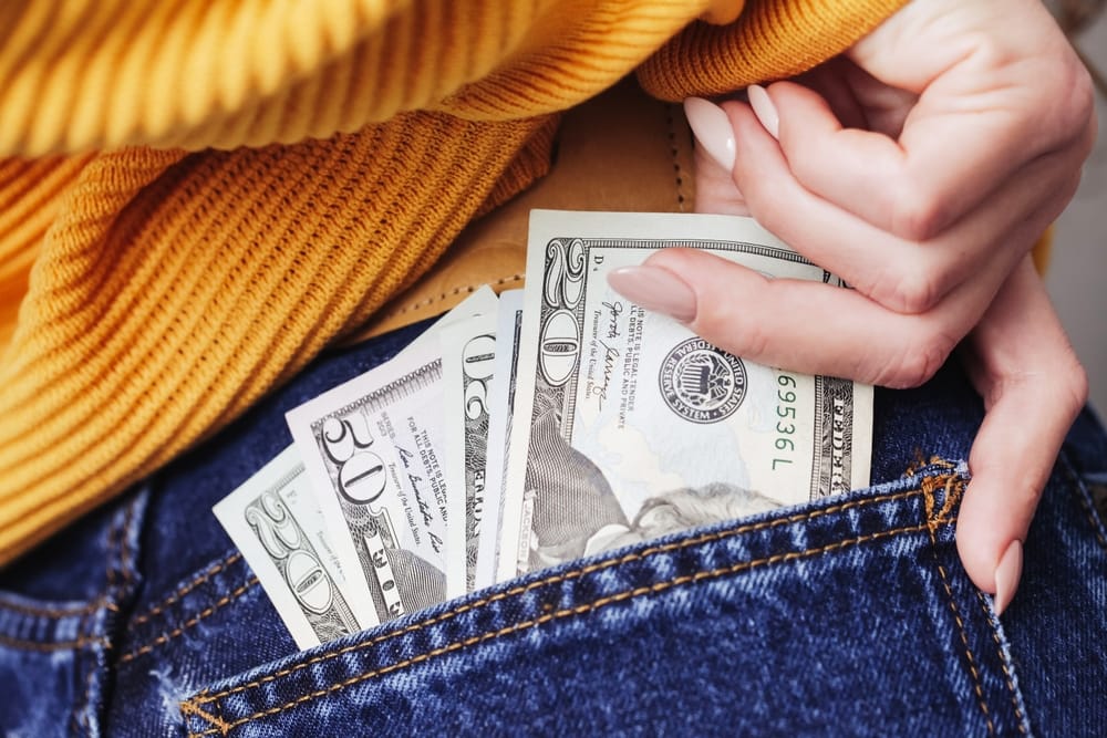 Money coming out of a woman's pocket.