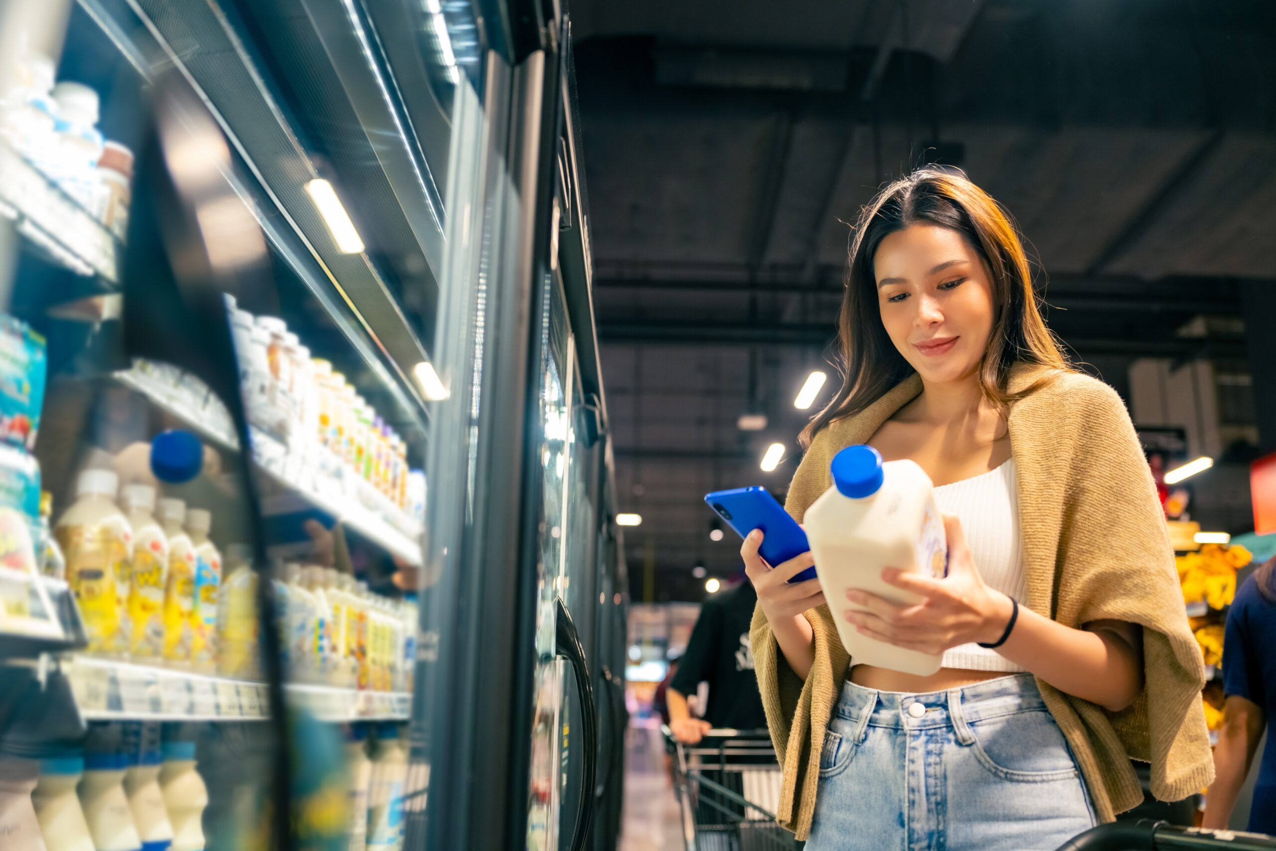 Woman checking the price of milk at a grocery store.
