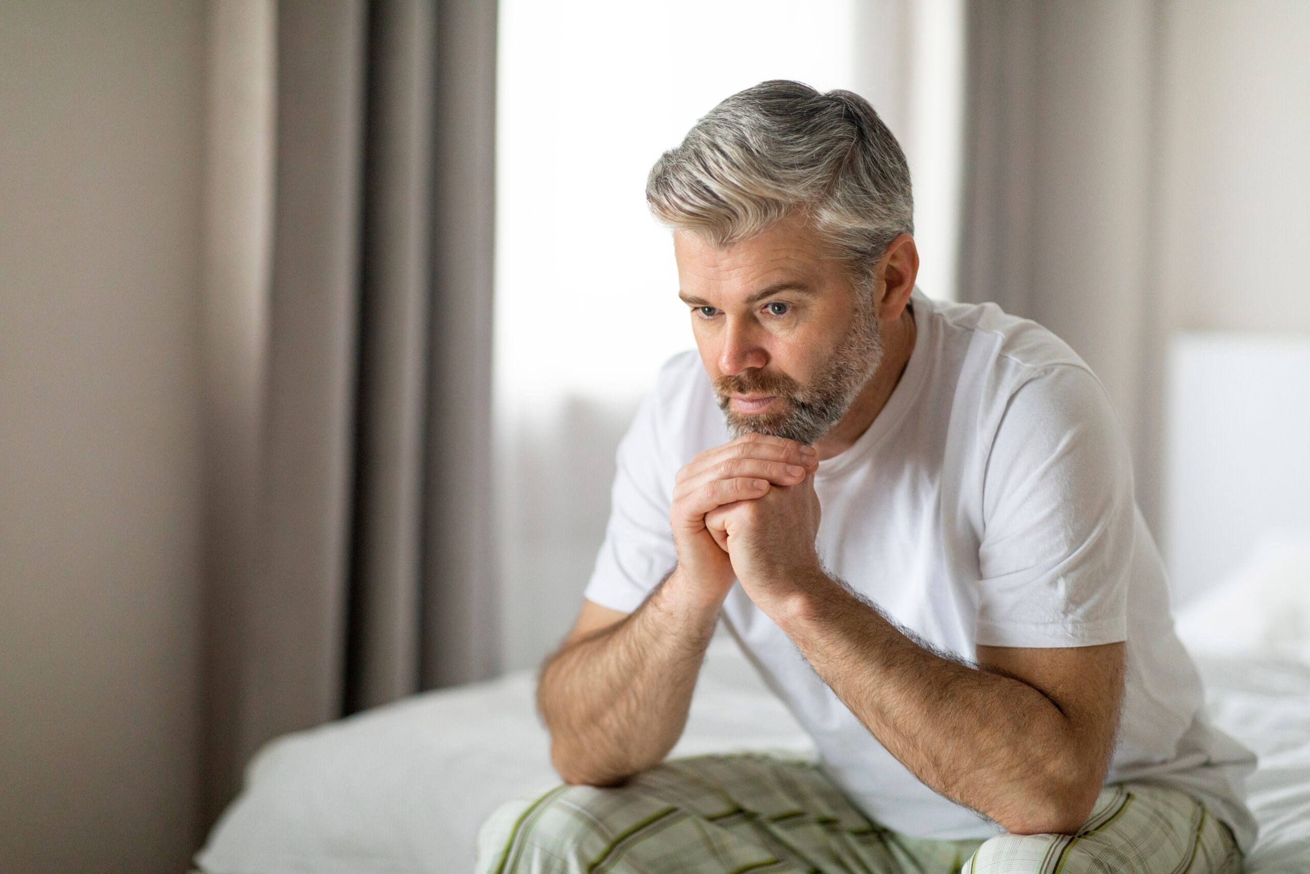 A middle aged man sitting alone thinking about his life.