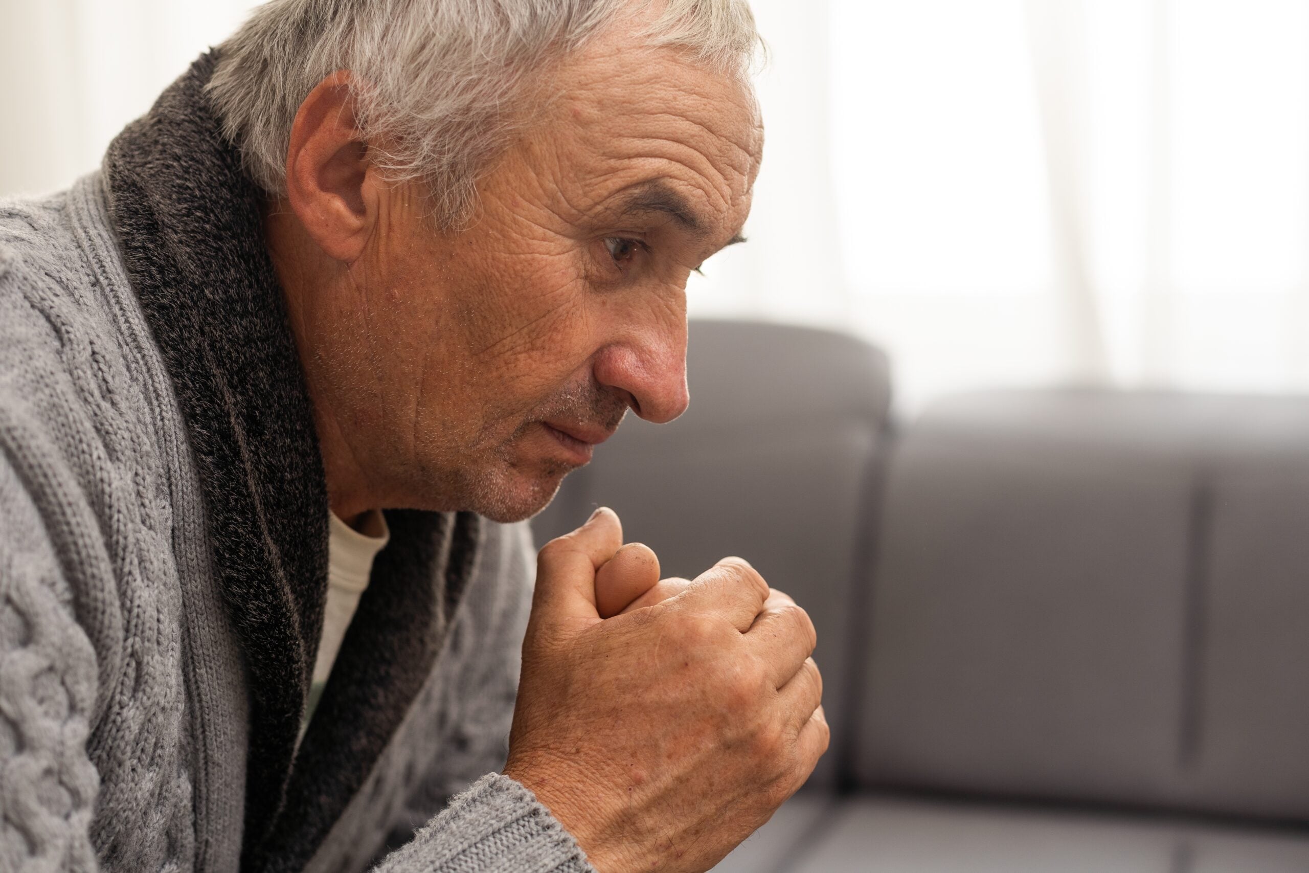 A senior man sitting alone deep in thought.
