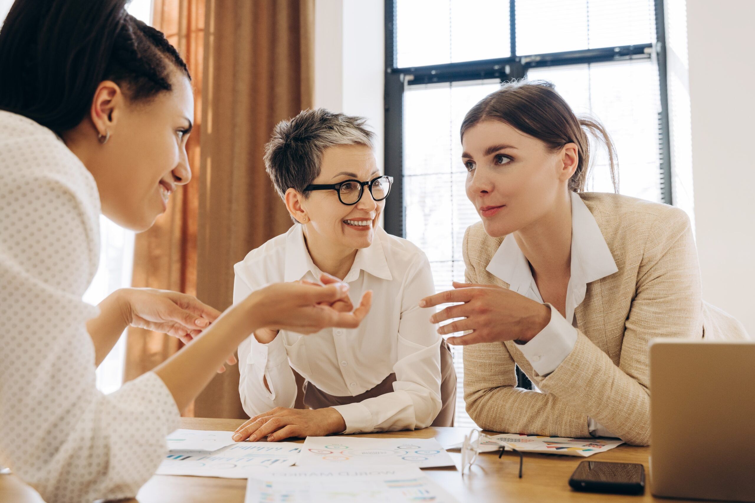 Three businesswomen are discussing work during a meeting in the office.