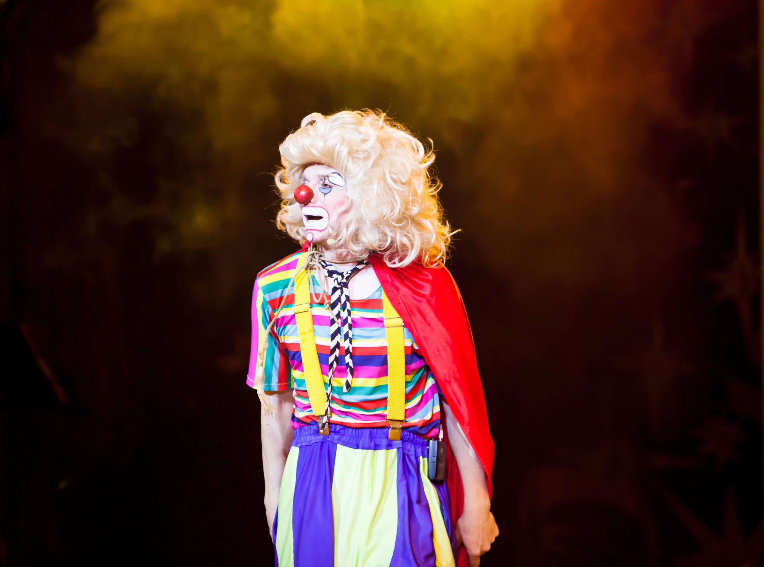 Clown performing on a dark stage.