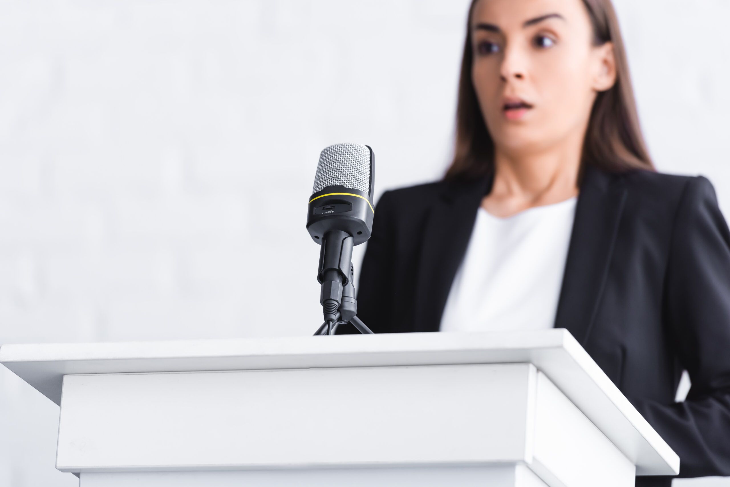 Young woman at podium panicking before giving a speech.