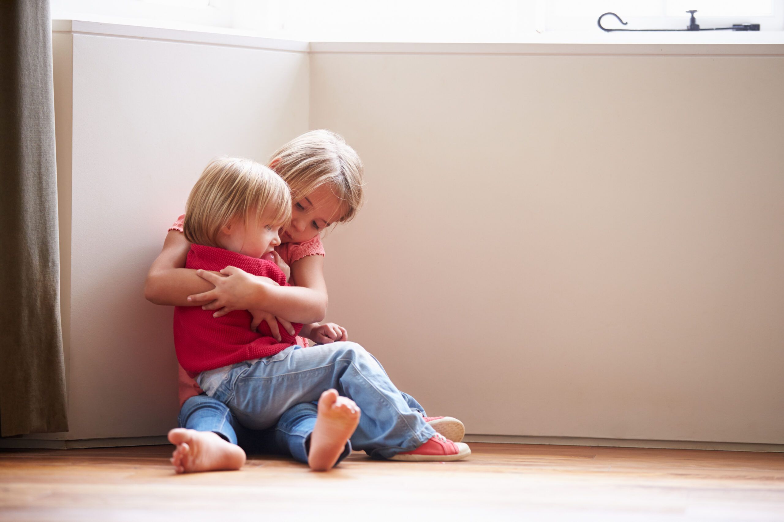 Two small siblings comforting one another.
