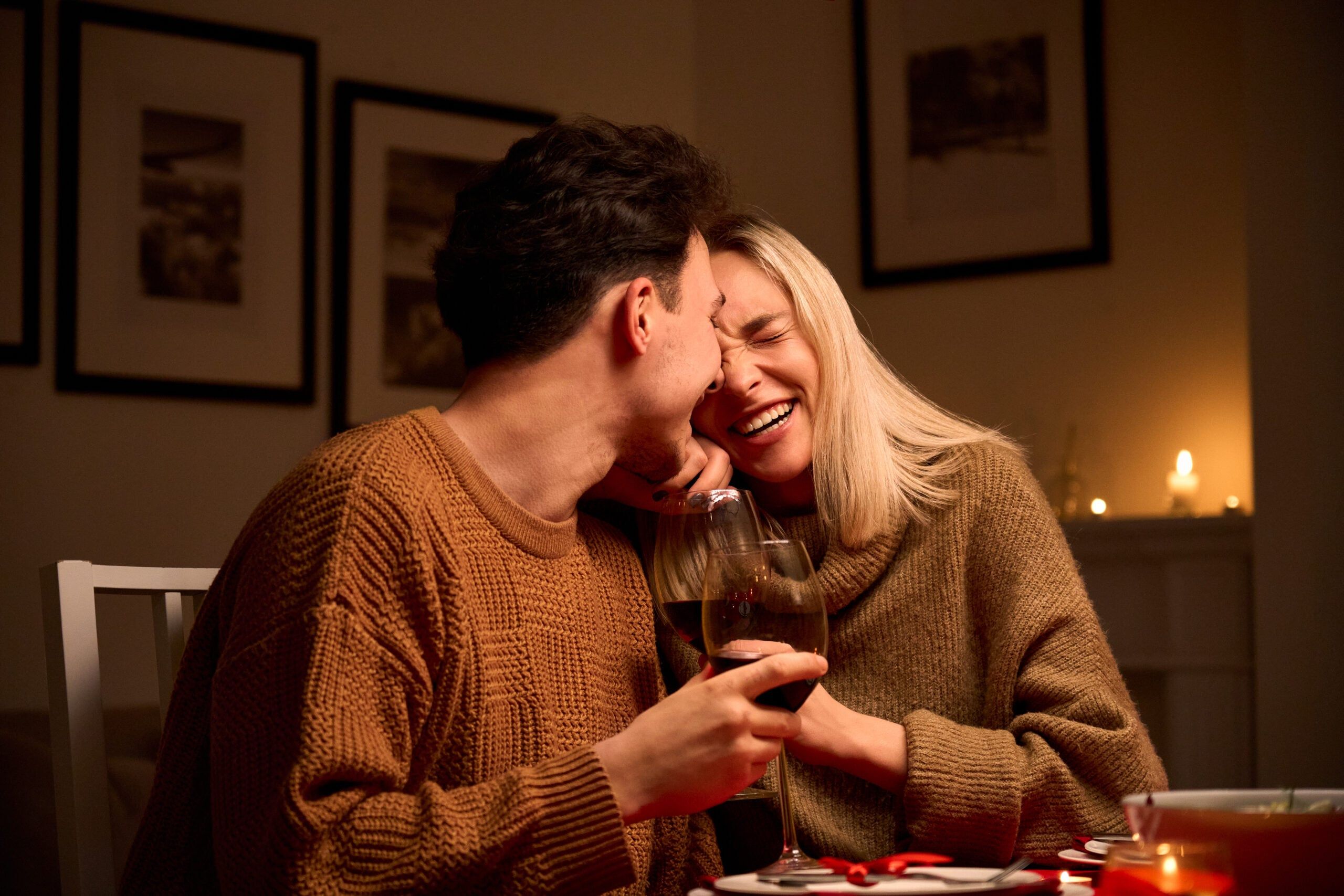 A happy young couple laughing and drinking wine on a date.