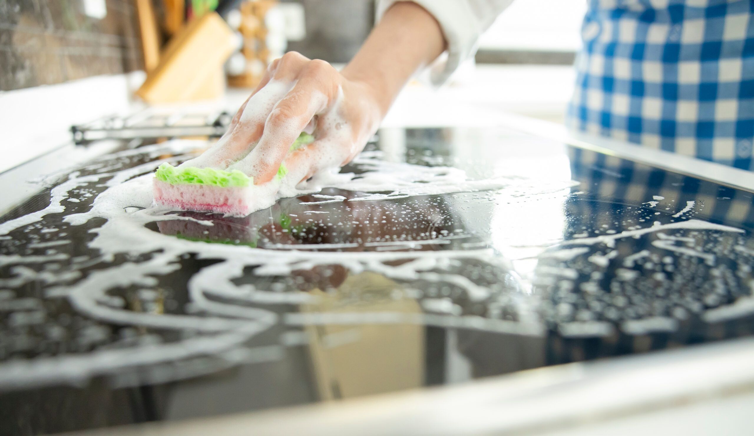 A woman multitasking while cleaning her stove.