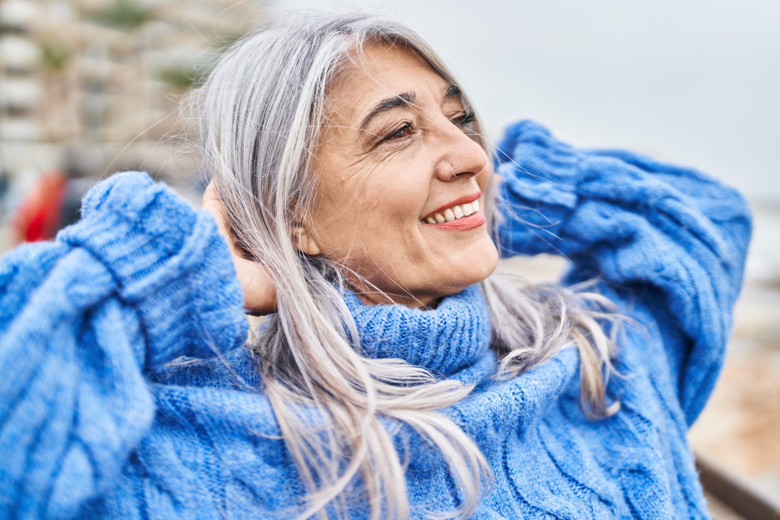 A liberated senior woman relaxing at the sea thinking about her children.