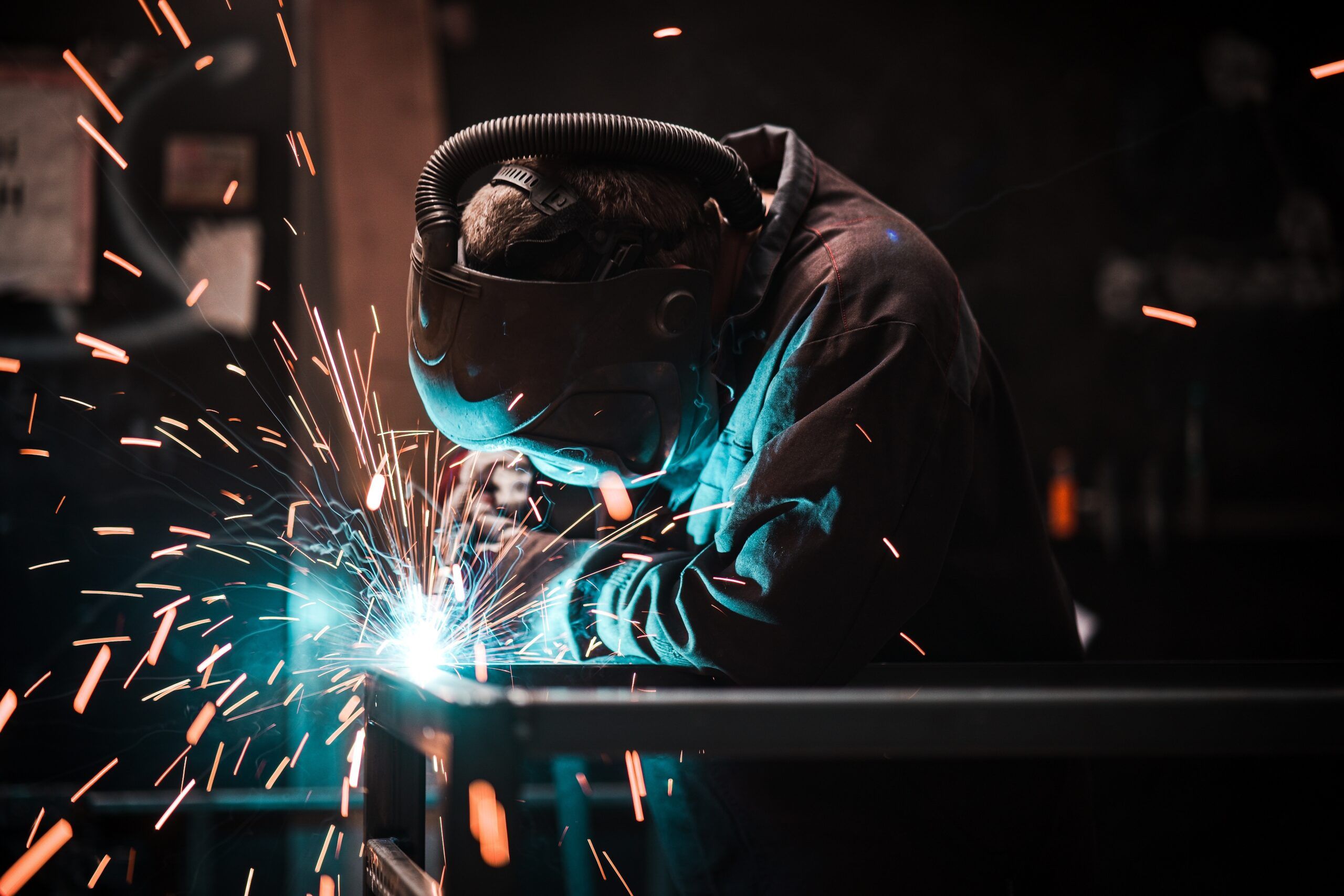 A trade worker welding iron in protective clothing.