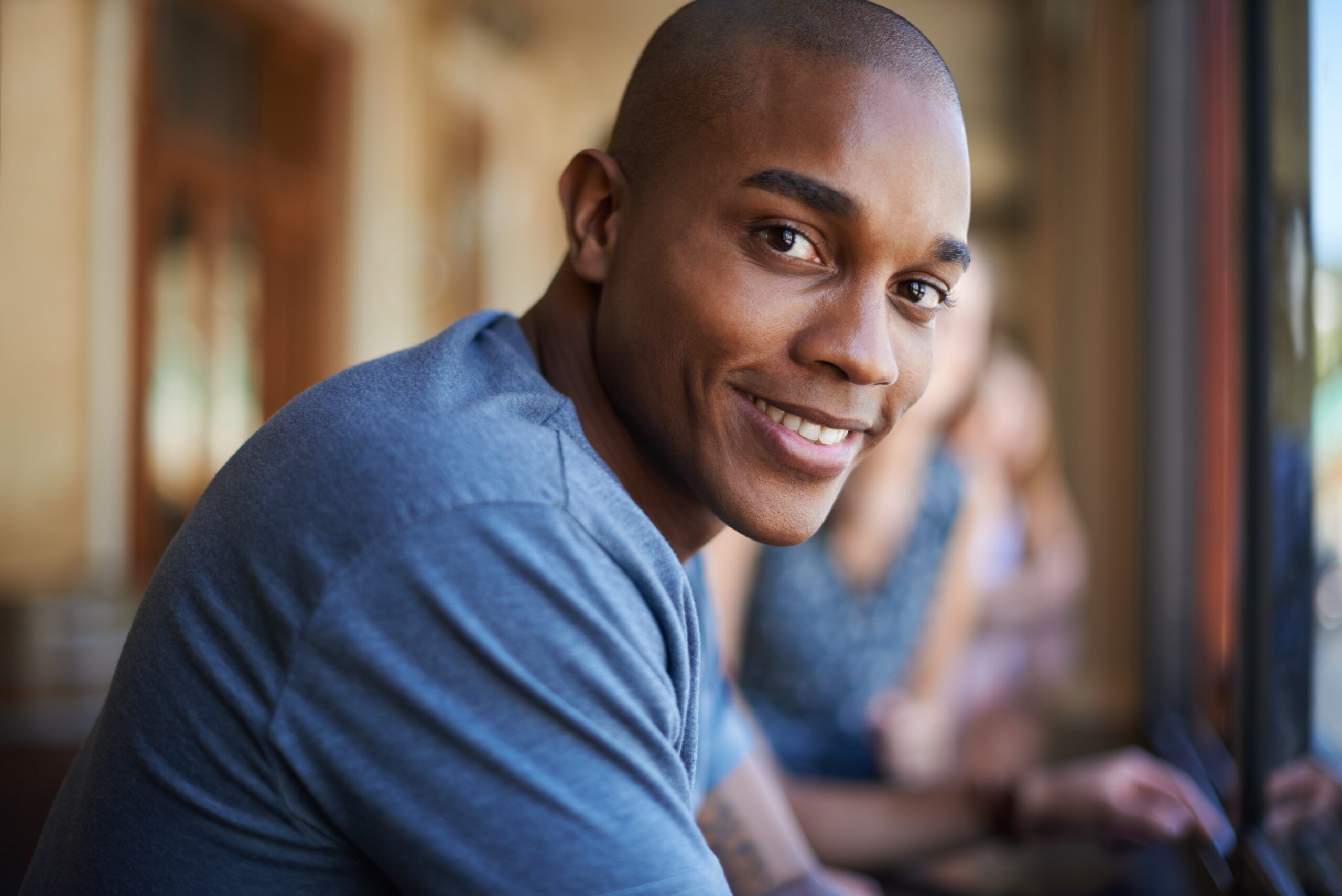 A warm and likable man sitting in a cafe alone.