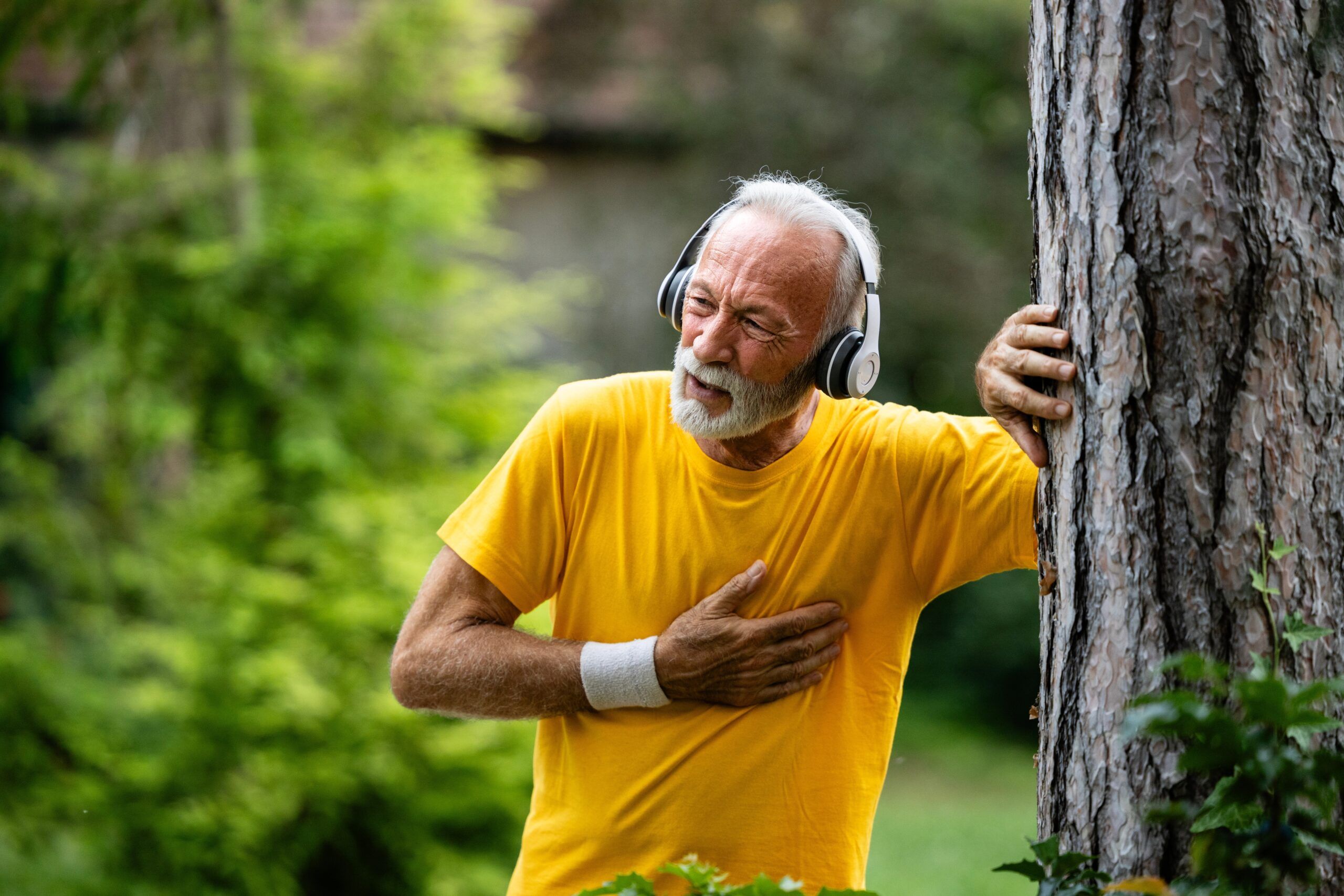 A senior man having health issues while jogging in the park.