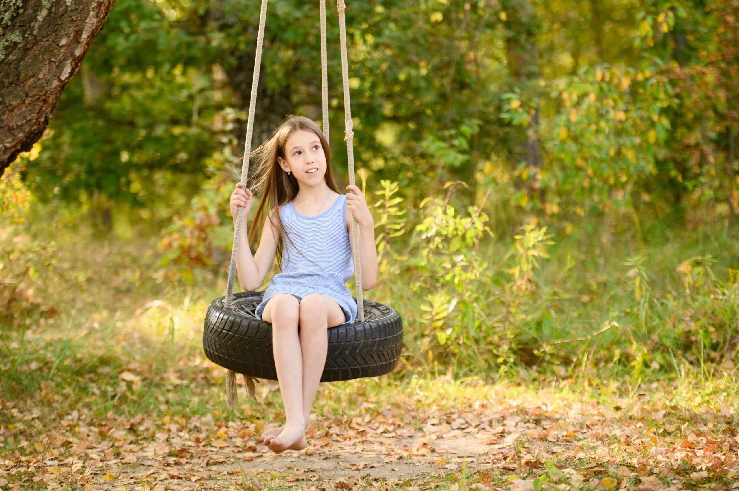 Young girl happily playing on a tire swing without any adult supervision.