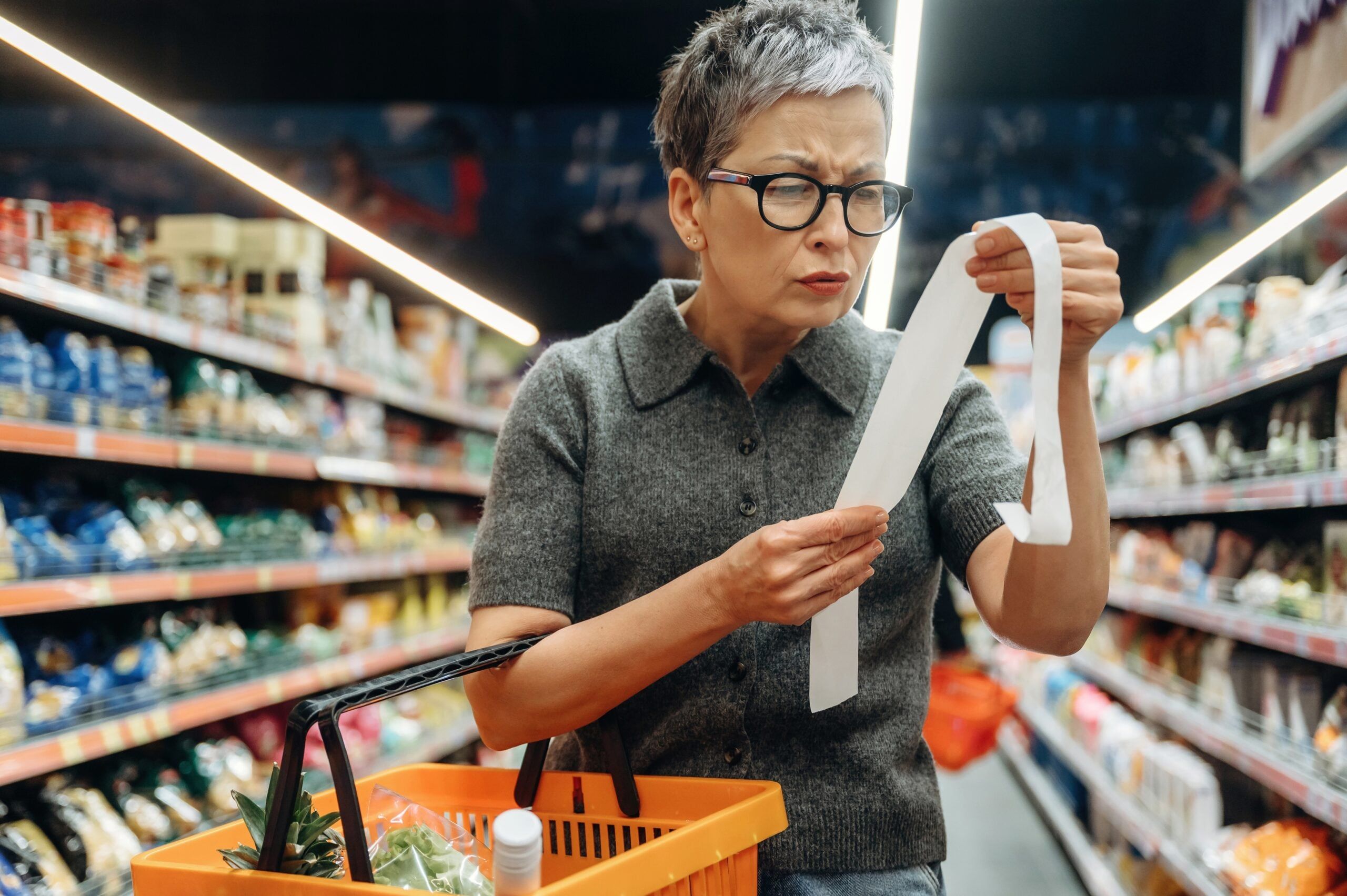 A mature woman shopping for groceries and counting every dollar.