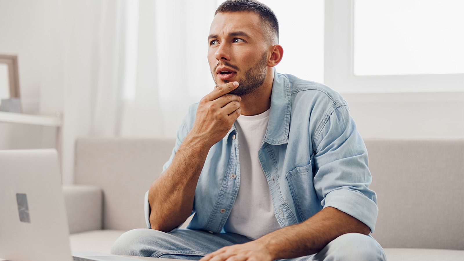 Man pondering life in his 40s, sitting in front of a computer staring into the distance thinking