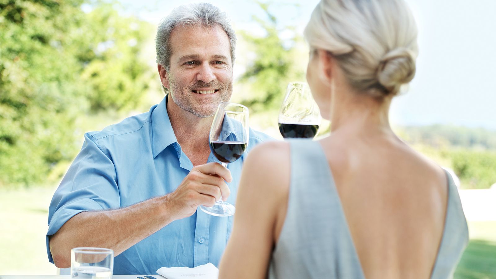 Enjoying a lunch date. Happy mature couple toasting their love with two glasses of wine while outdoors.