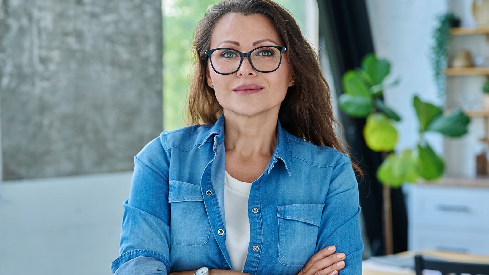 Confident woman in her 40s, wearing glasses, smiling confidently