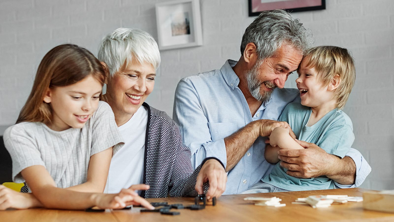 Portrait of grandparents and grandchildren having fun together playing domino game at home