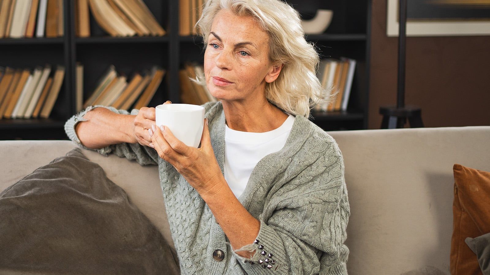 omfort relaxed senior old elderly woman drinking hot beverage tea coffee in sofa at home