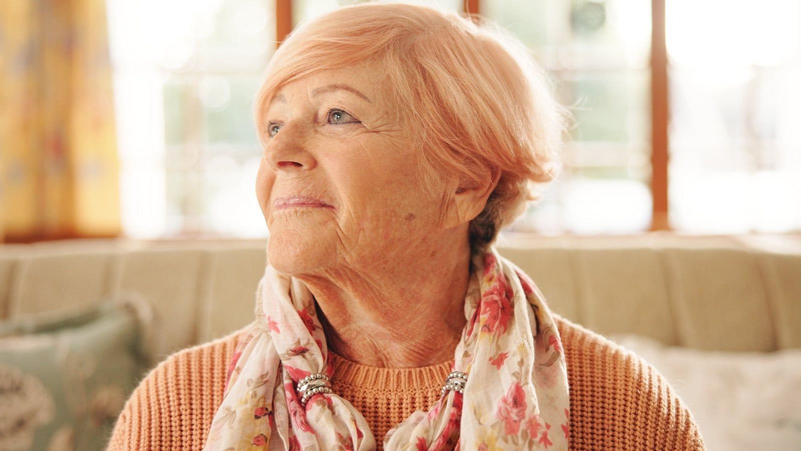 Happy, thinking and senior woman in home with hope, nostalgia and memory with vision.