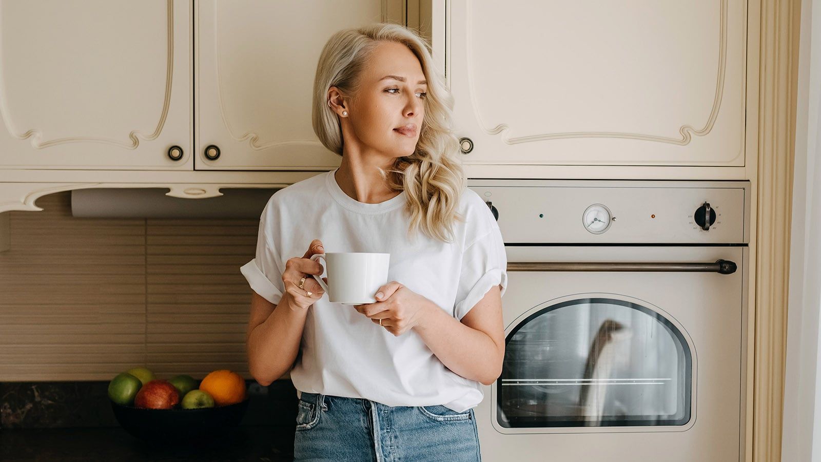 Young woman in kitchen holding a cup of coffee in the morning.