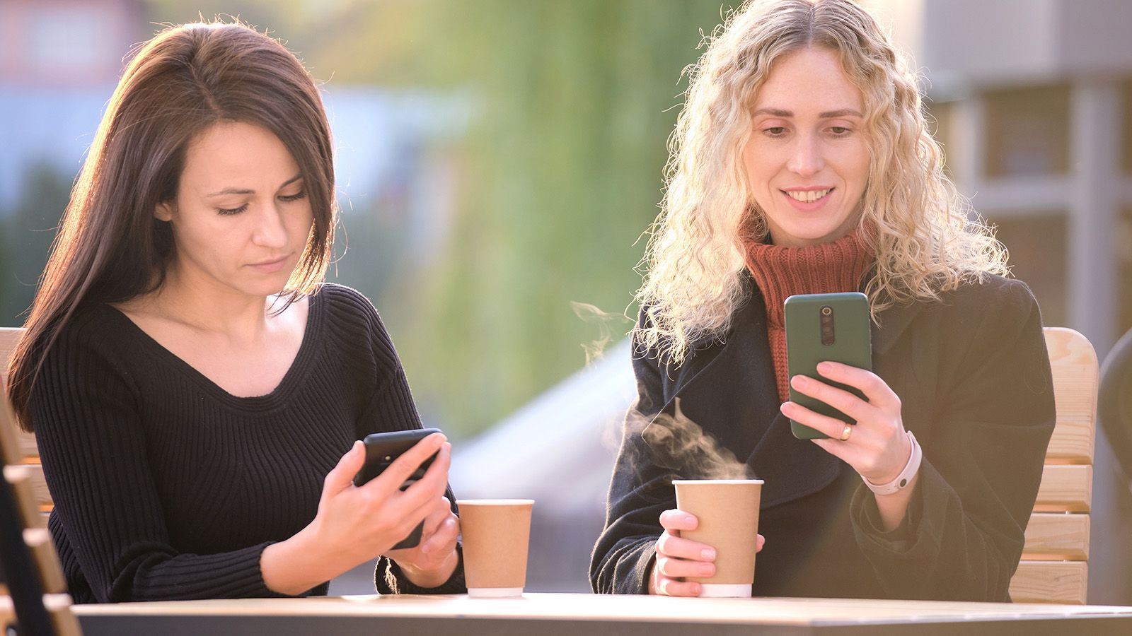Two women ignoring each other on their phones when they should probably put them down.