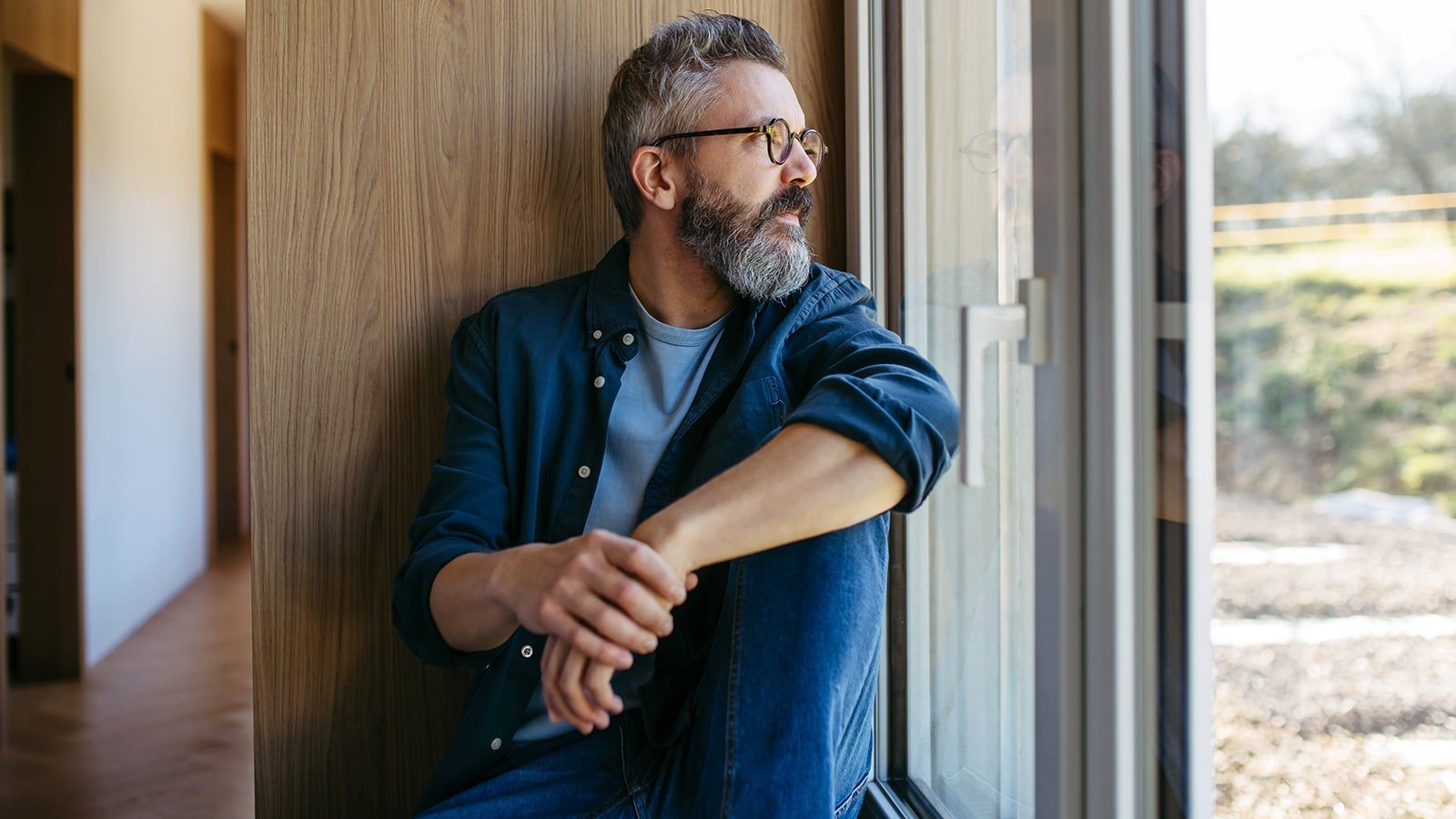 Middle aged man sitting by window and thinking.